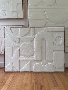 three white abstract paintings on the wall in a room with wood floors and hard wood flooring