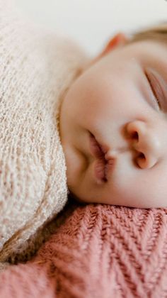 a baby sleeping on top of a pink blanket