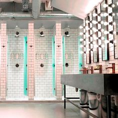 a bathroom with three urinals in it and several lights on the wall above them