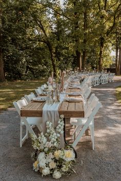 a long table set up with white flowers and greenery for an outdoor wedding reception