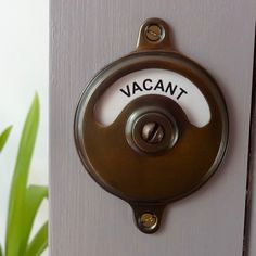 a door handle with the word vacant on it and a potted plant in the background