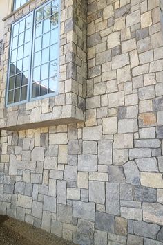 a cat sitting on a ledge in front of a stone building with a large window