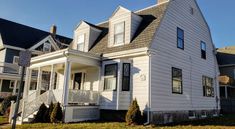 a large white house with two storys and a porch on the second floor in front of it