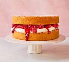 a cake with strawberries and whipped cream on top is sitting on a white pedestal