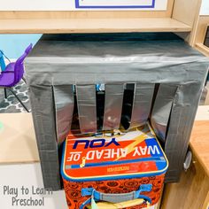 an old school lunch box sitting on top of a metal trash can in the middle of a classroom