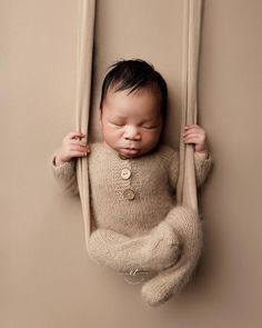 a baby in a sweater is hanging upside down on the wall with his head between two poles