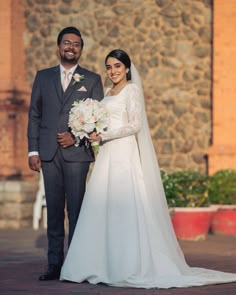 a bride and groom standing in front of a stone building