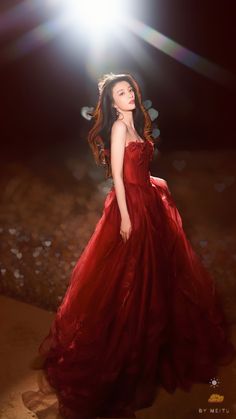 a woman wearing a red dress standing in front of a bright light on the ground