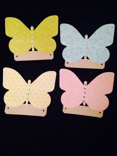 four different colored paper butterfly clips on a black background with polka dotes and pearls