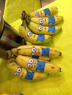 bananas with eyes painted on them sitting next to a cup