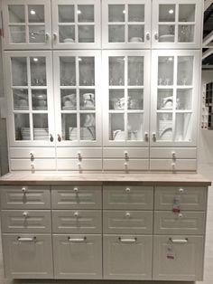 the cabinets are all white and have drawers with glass doors on each side that is open