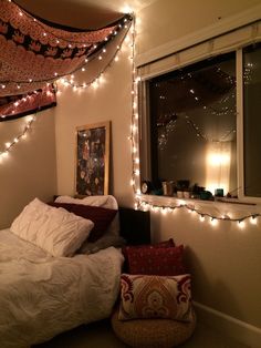 a bedroom with lights strung over the headboard and bed in front of a window