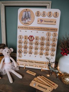 a teddy bear sitting on top of a table next to a calendar and magnets