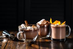 two mugs filled with hot chocolate and topped with orange peel garnishes