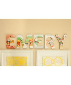 the word emery written in large letters on a wall above two framed pictures with yellow accents