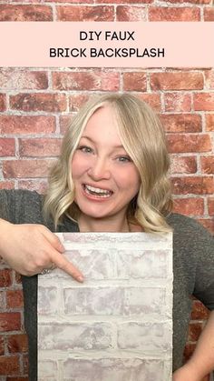 a woman pointing at a brick wall with the text diy faux brick backsplash