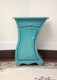 a blue cabinet sitting on the floor next to a white wall and tiled flooring