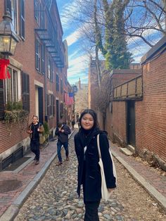 a woman walking down a cobblestone street