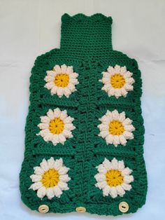 a green crocheted bag with white and yellow flowers