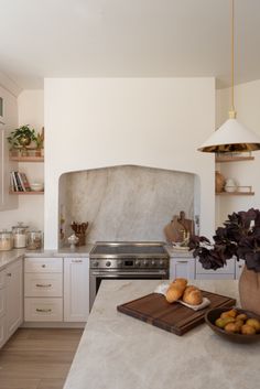 a kitchen with white cabinets and an island in the middle is filled with fruits and vegetables