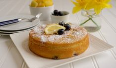 a cake on a plate with blueberries and lemons