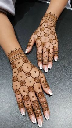 two hands with henna tattoos on them, one is white and the other is brown