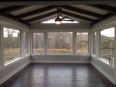 an empty room with large windows and wood flooring on both sides of the room