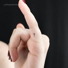 a woman's finger with a small cross tattoo on it