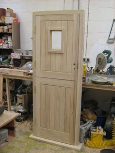 a large wooden door sitting inside of a room next to a workbench and tools