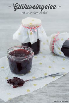 two jars of jam sitting on top of a table next to a knife and spoon