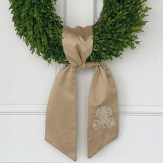 a wreath with a monogram on it hangs on the front door and is adorned with a satin ribbon