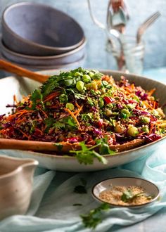 a salad in a bowl on a table with other dishes and utensils around it