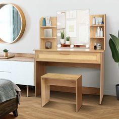 a wooden desk with a mirror and stool in a room next to a potted plant