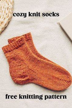 an orange knitted sock sitting on top of a bed next to a laptop computer