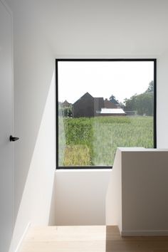 an empty room with a large window looking out onto a farm field and barn in the distance