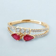 a gold ring with two red stones on top and one white stone in the middle