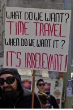 a man holding a sign that says what do we want? time travel when due what it? it's irrecevant