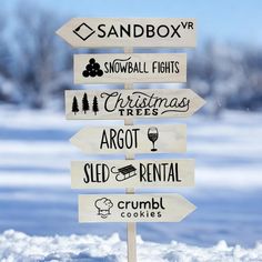 a wooden sign with several different types of signs on it in front of snow covered ground