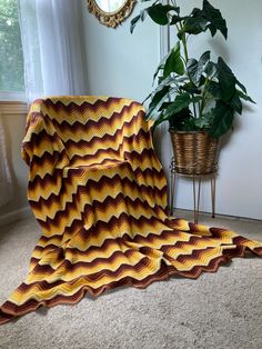 a blanket is laying on the floor next to a potted plant and a mirror