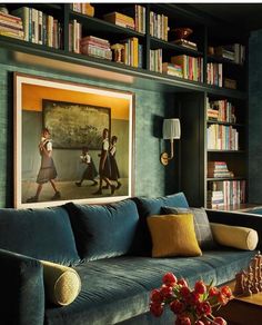 a living room with bookshelves, couches and pictures on the wall above