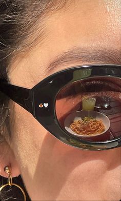 the reflection of a woman's eye in her glasses with food on it and a drink