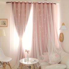 a living room with white furniture and pink curtains