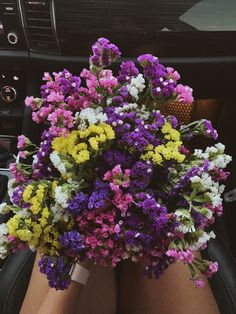 a bunch of flowers that are sitting in the back seat of a car with someone's legs