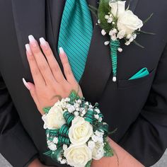 a close up of a person wearing a suit and tie with flowers on their wrist