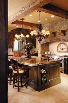 a large kitchen with an island and chandelier in the center, surrounded by wooden cabinets