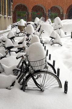 several bicycles are covered with snow in front of a building