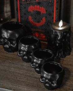 four black candles sitting on top of a wooden table next to a skull candle holder