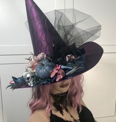 a woman with pink hair wearing a purple witches hat