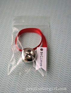 a red rubber bracelet with a metal ball on it's end and a tag attached to the clasp