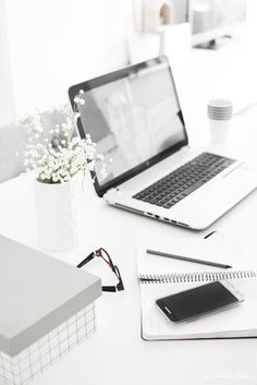 an open laptop computer sitting on top of a white desk next to a cup of coffee